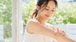 夏の日差しの中で腕の肌に触れる女性（医療脱毛イメージ）
